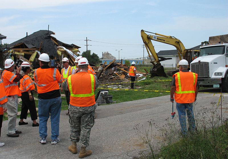 Omni Construction crew in reflective vests and hard hats overseeing debris pickup after a hurricane